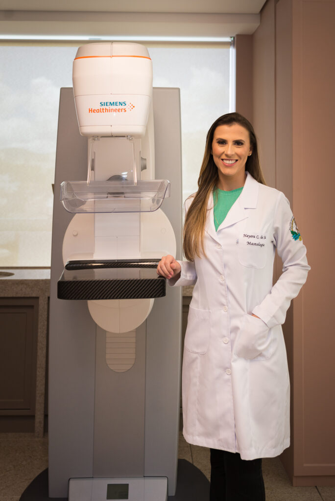 Dra. Nayara Carvalho de Sá, mastologista em Belo Horizonte, ao lado do aparelho de mamografia usado no diagnóstico de microcalcificações