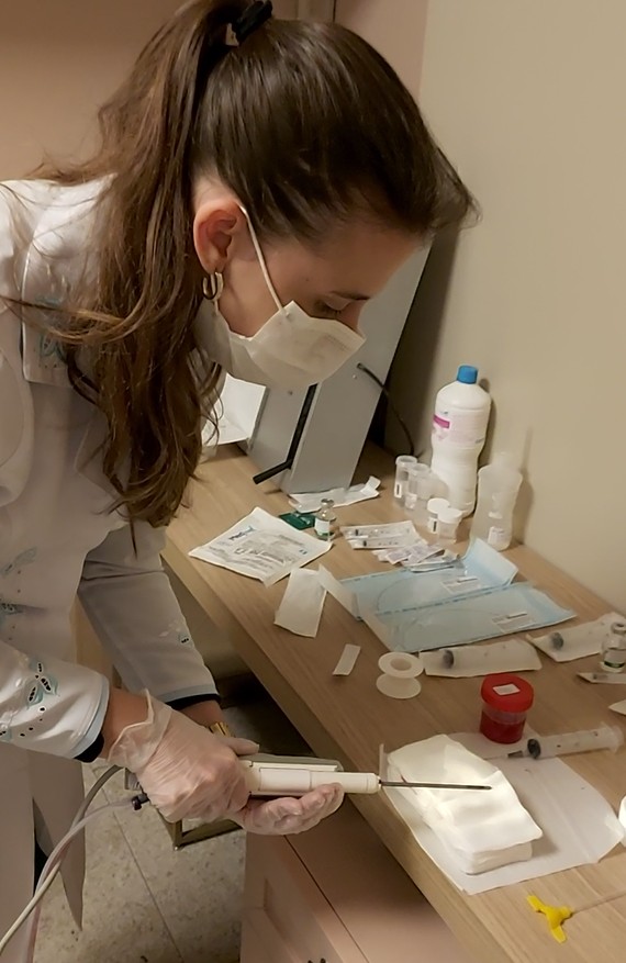 Dra. Nayara Carvalho, de máscara e luvas, prepara a agulha do sistema de biópsia a vácuo na bancada de materiais estéreis
